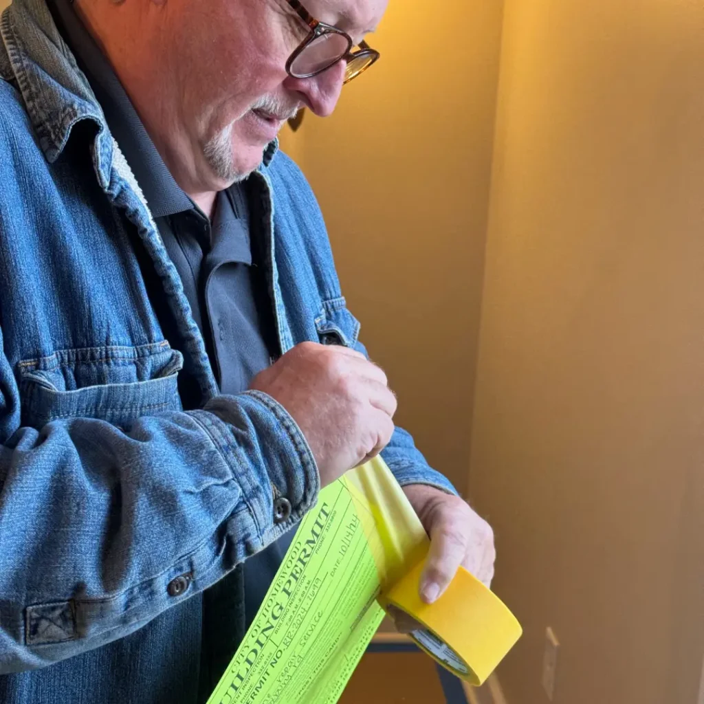 Kevin Cato, a Licensed and Insured Deck Contractor in Hoover, hanging a building permit to ensure code compliance before starting a project